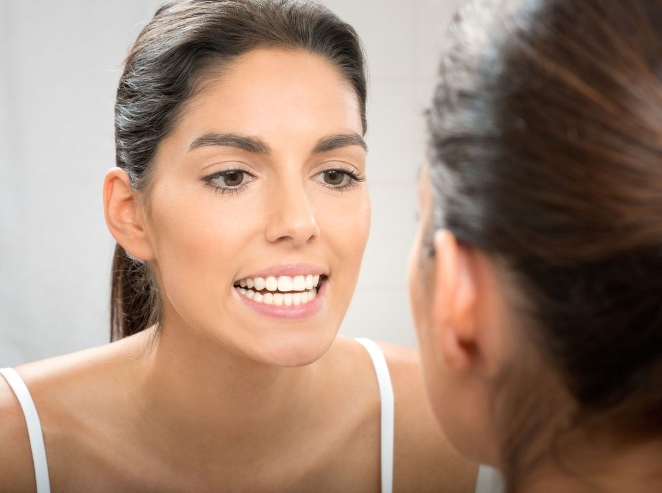 Woman analyzing teeth in mirror